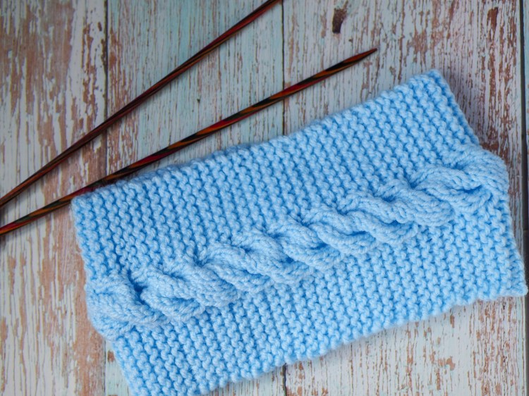 This is a blue headband with a cable showing the finished garment from this headband knitting pattern